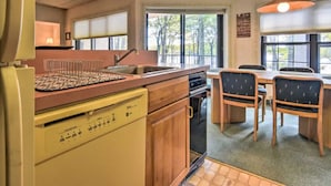 Una cocina funcional con lavavajillas integrado, un comedor con mesa y sillas, y un amplio ventanal que proporciona luz natural.