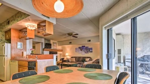 Un espacio habitable compacto con comedor, cocina y un amplio ventanal corredero que da a un área exterior.