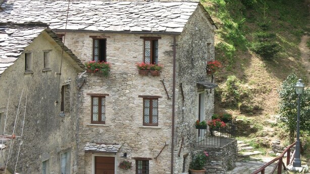 Ein Gebäude aus Stein mit mehreren Fenstern, einer Tür und Blumenkästen an der Fassade.