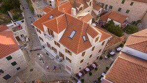 Ein Gebäude aus Stein mit rotem Ziegeldach, mehreren Balkonen und Außenbereichen mit Sitzgelegenheiten.
