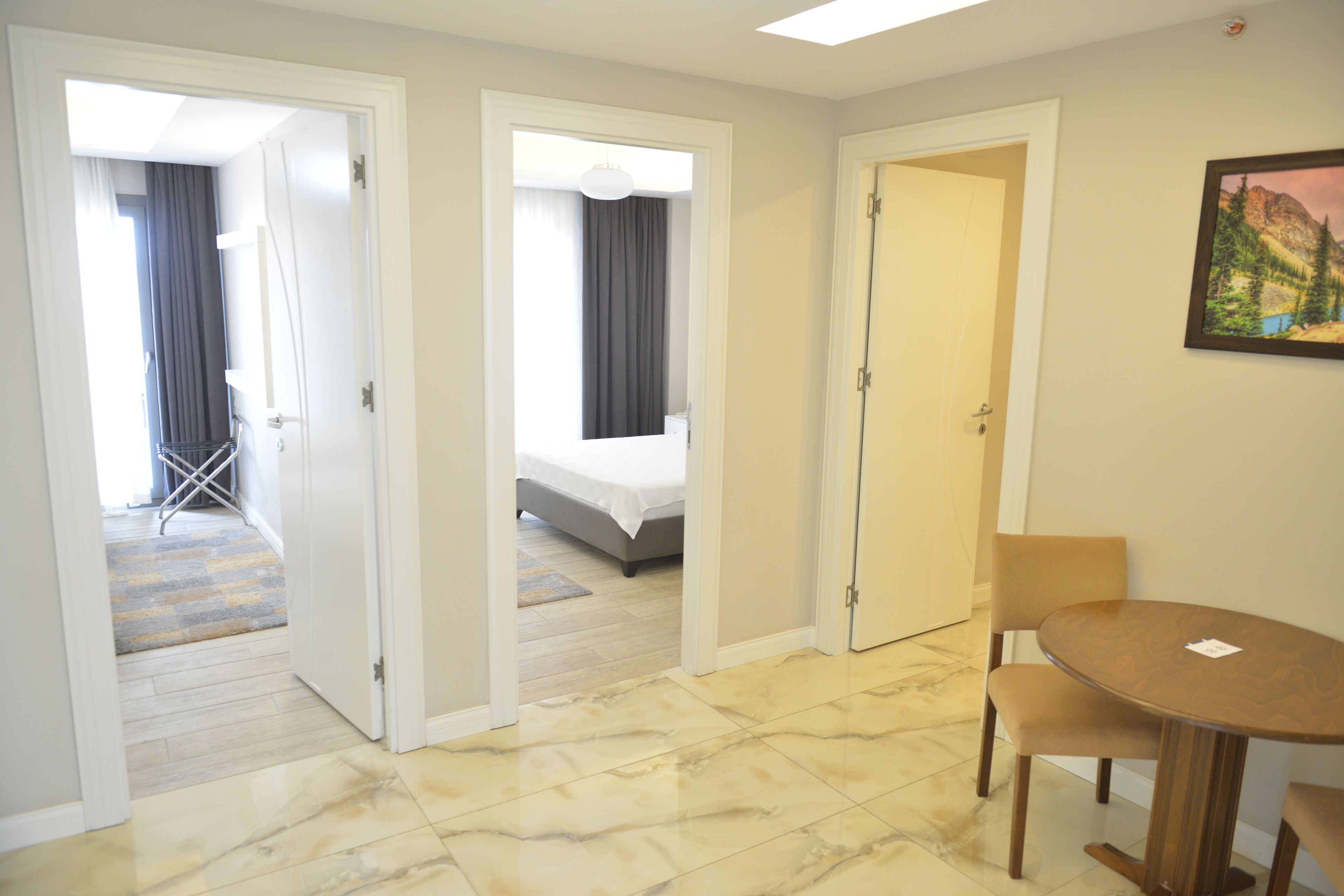 A hotel room with a bed, a dining table with chairs, and a painting on the wall.