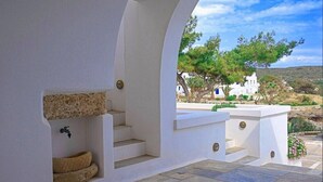 A white outdoor staircase leading to a terrace with a view of white buildings and trees. - Maryianni Apartments (Kithira)