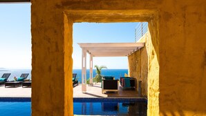 A poolside area with lounge chairs and a view of the sea. - Yellow Dream Villas (Chania)