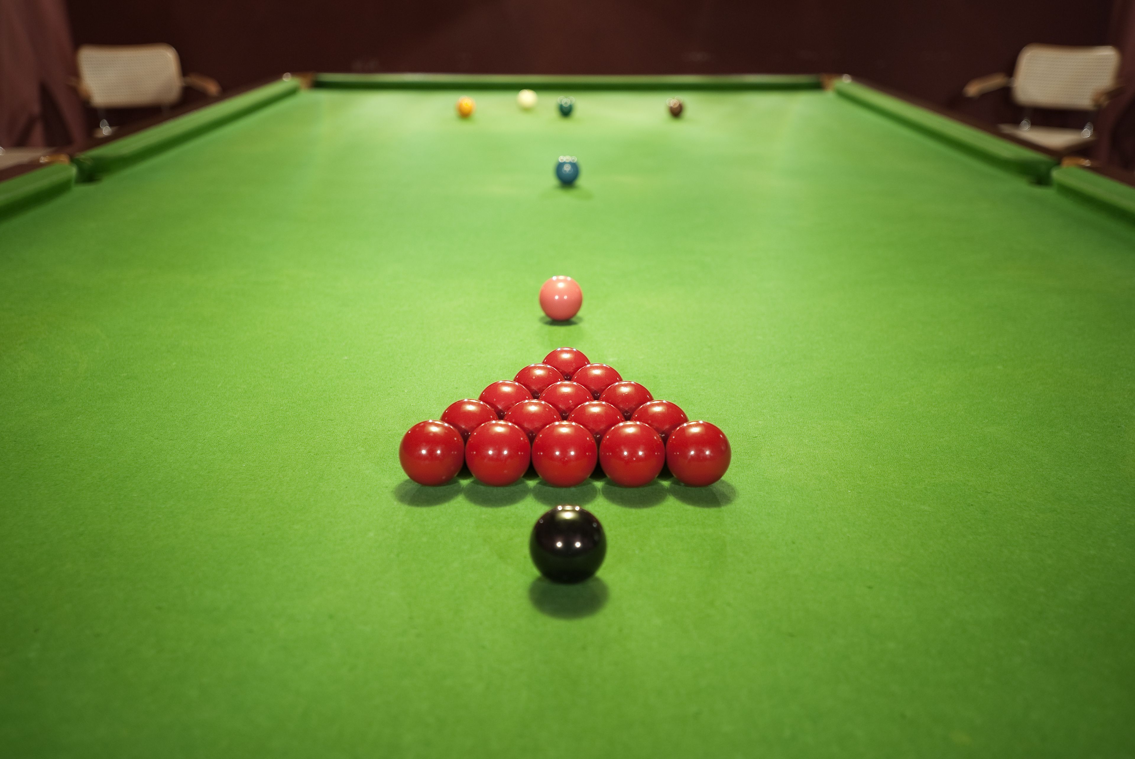 A pool table with a triangular arrangement of red balls and a single black ball in the center.
