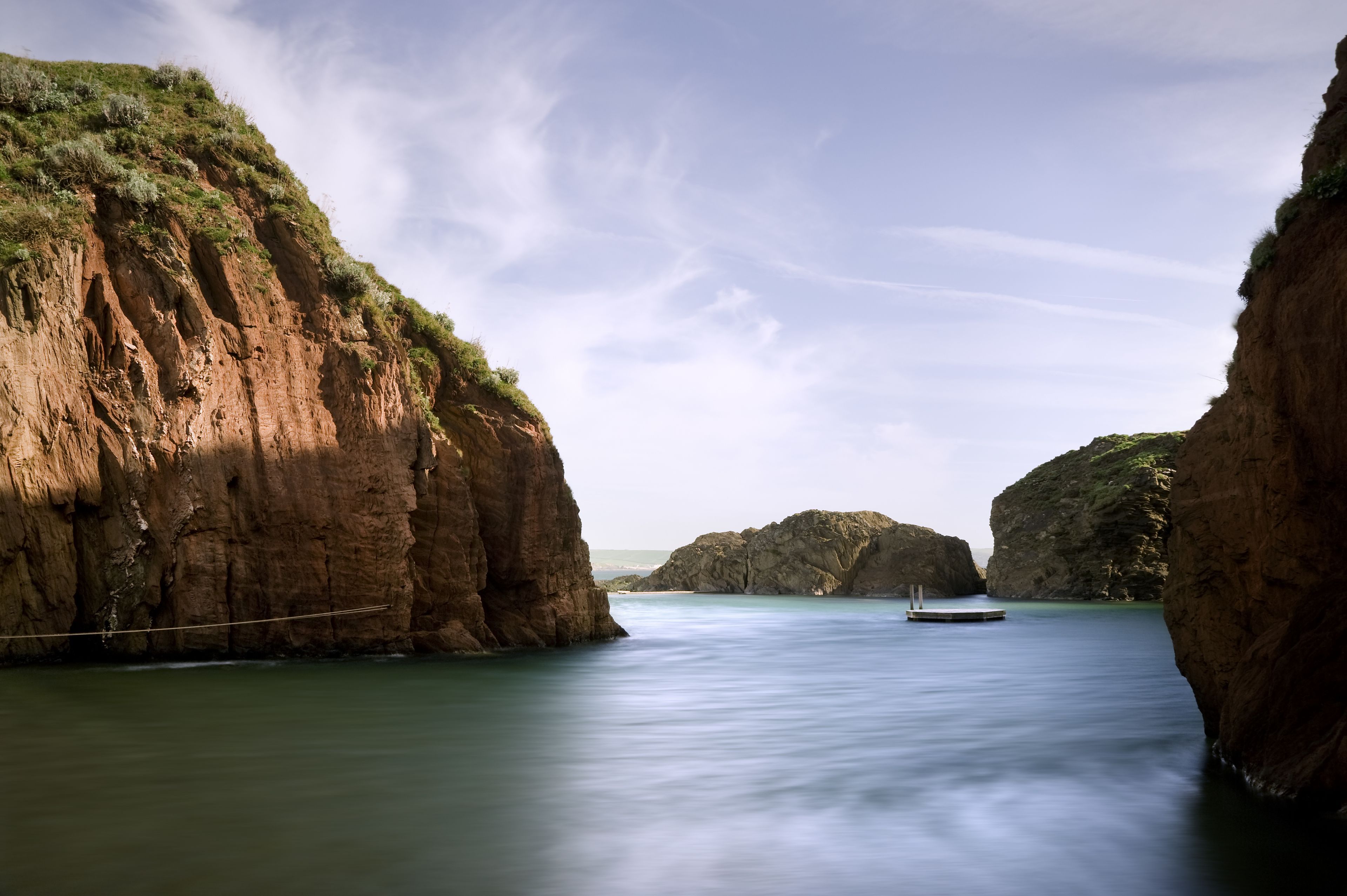 Paisagem costeira com falésias rochosas e águas calmas.