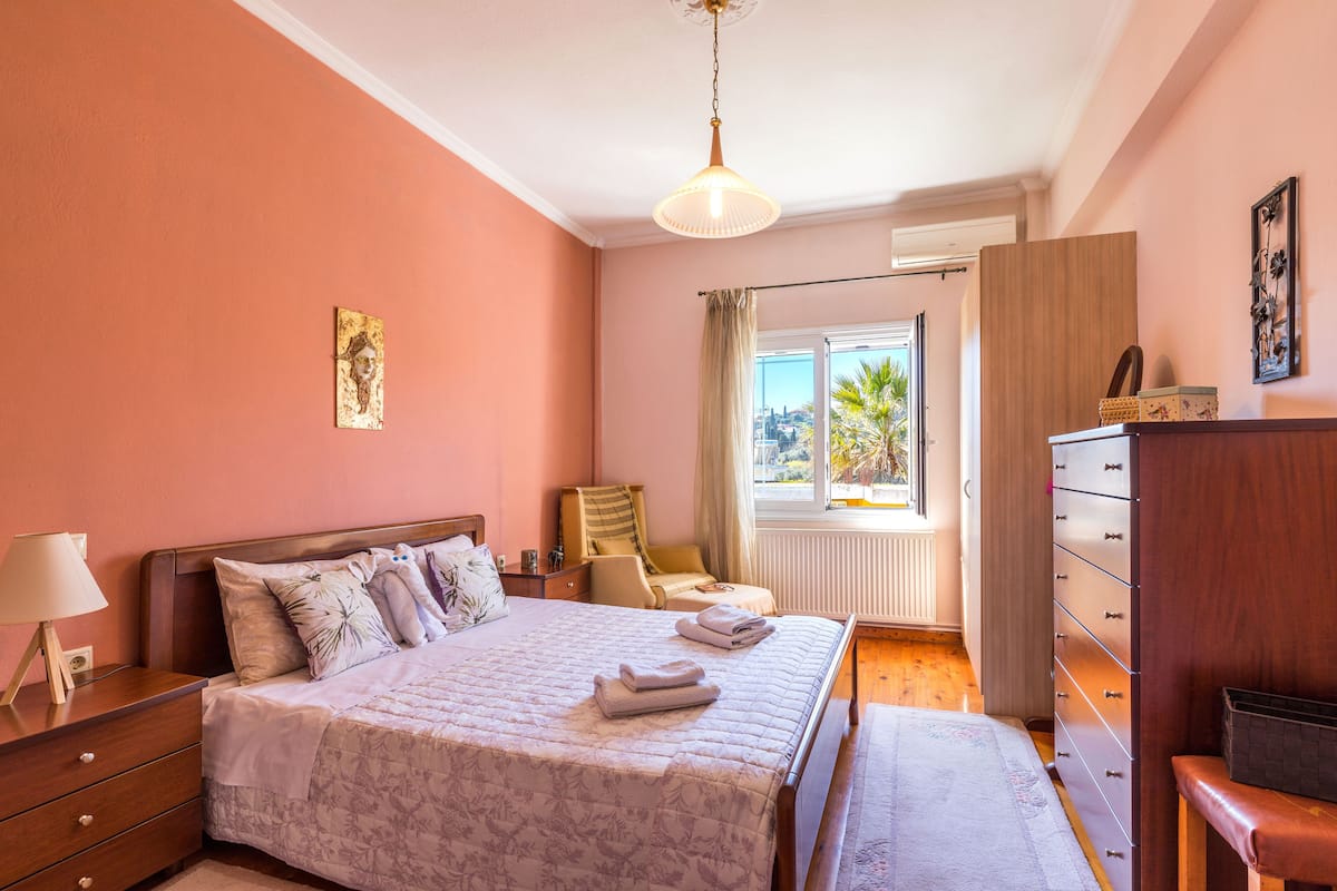 A bedroom with a bed, dresser, and a window with a view.