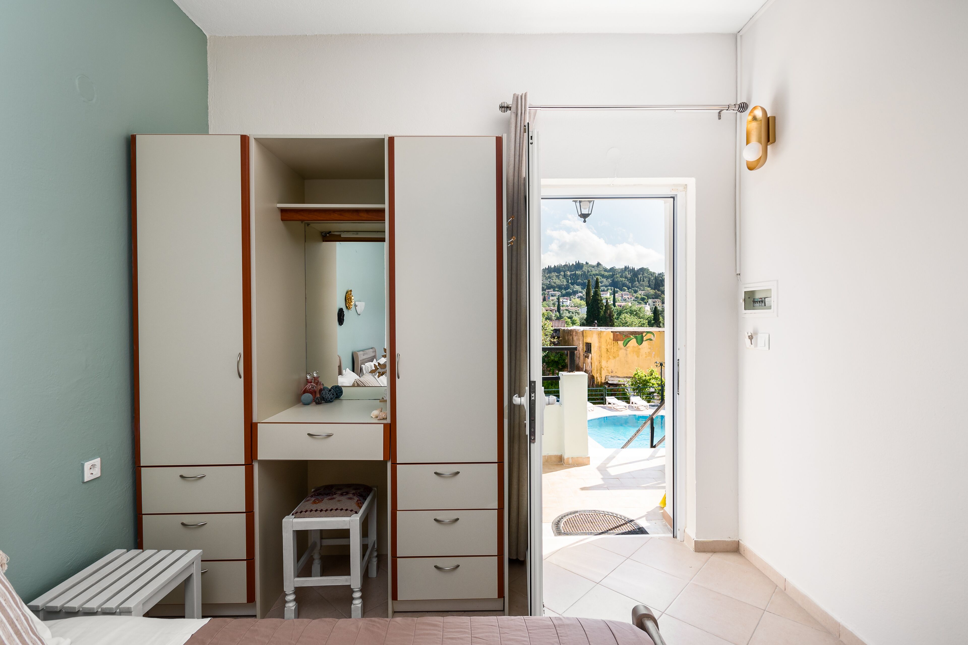 Un dormitori amb un armari ampli, un escriptori petit i vista a una piscina.