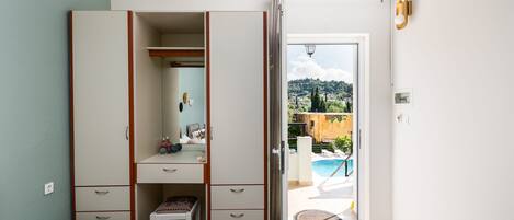 Un dormitori amb un armari ampli, un escriptori petit i vista a una piscina.