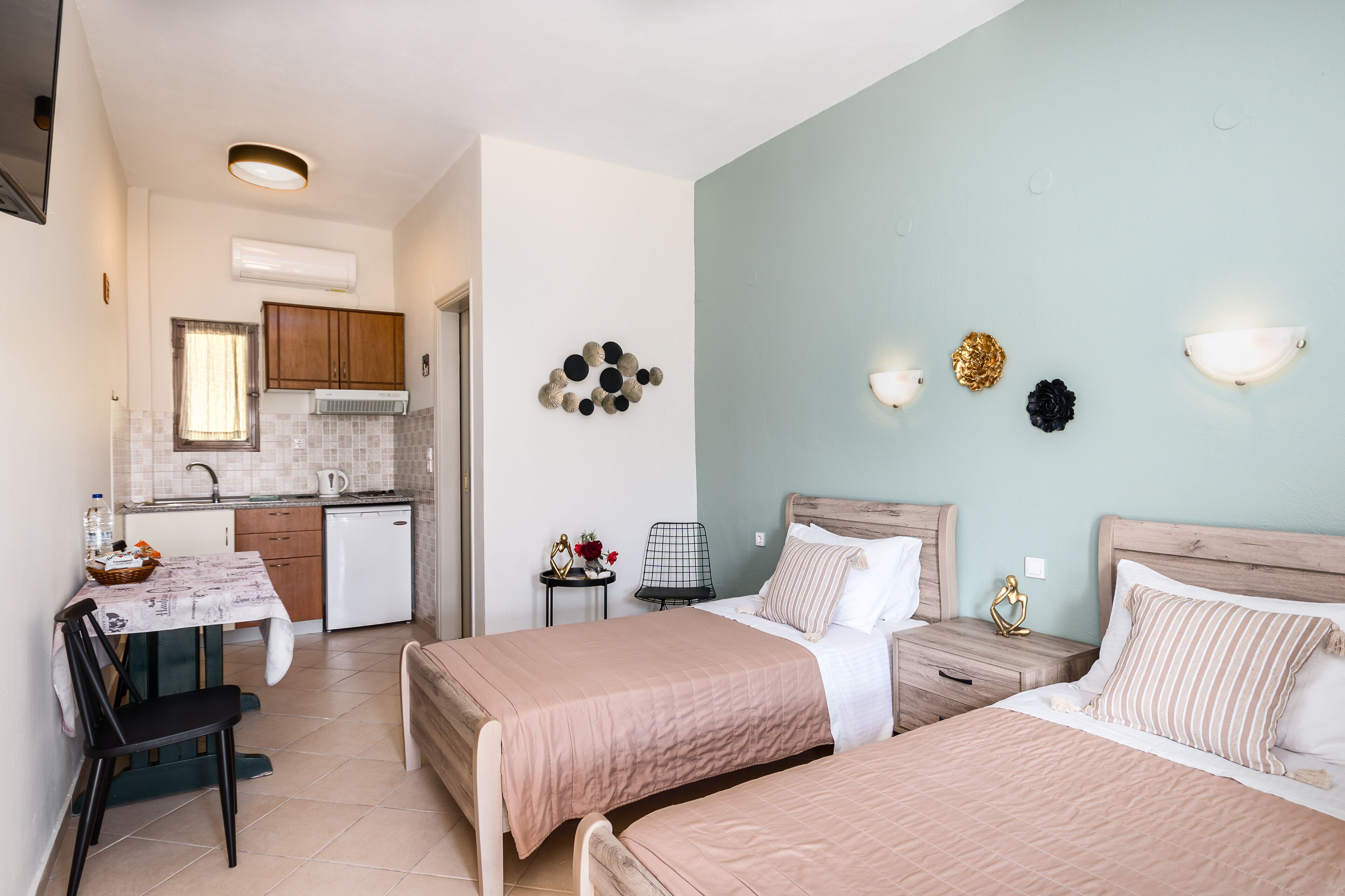 A bedroom with two beds, a bedside table, a nightstand, a chair, and a small table with a basket.
