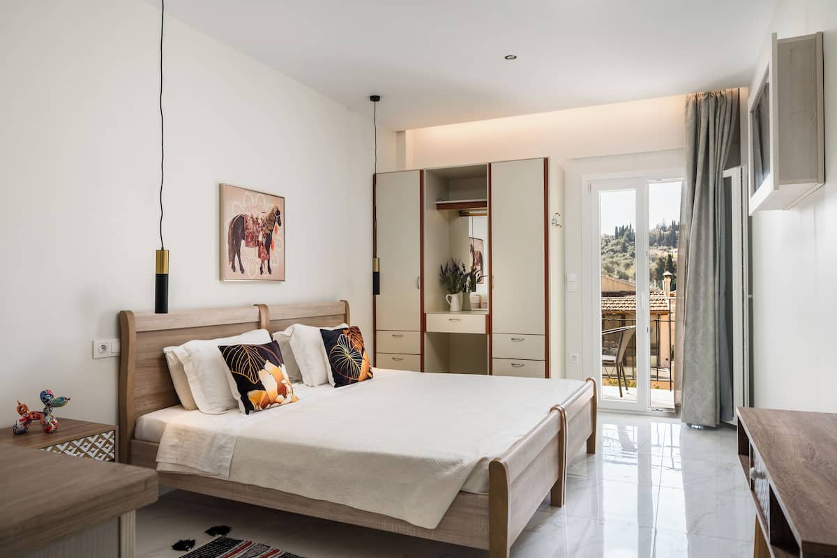 A bedroom with a bed, bedside table, wardrobe, and a view through a sliding door.