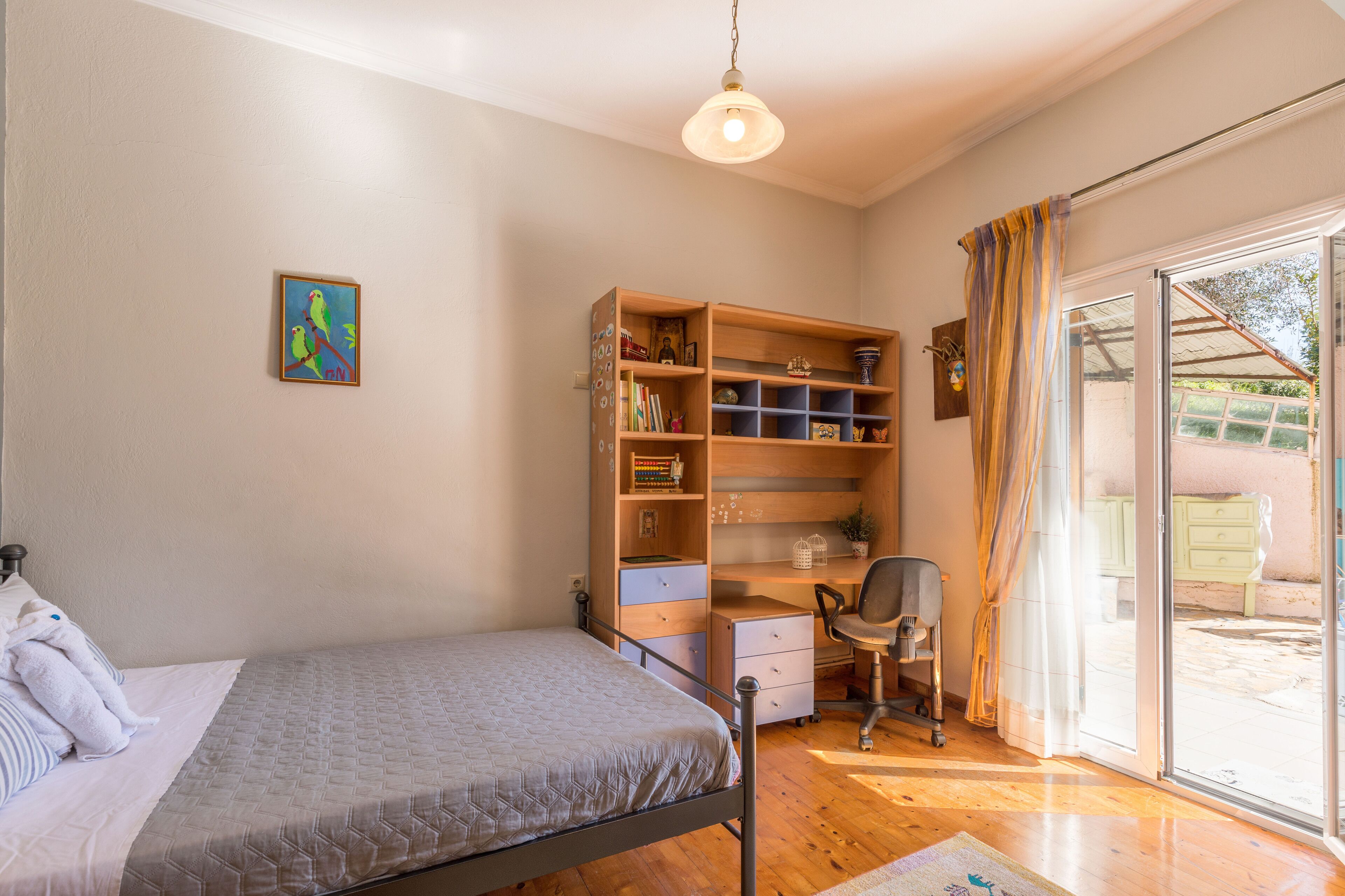 Een slaapkamer met een bed, een bureau, een stoel en een boekenkast.