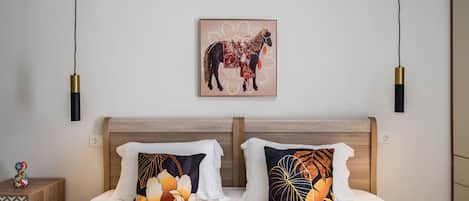 A neatly made bed with two pillows, a wall-mounted artwork of a horse, and a bedside table with a decorative item.