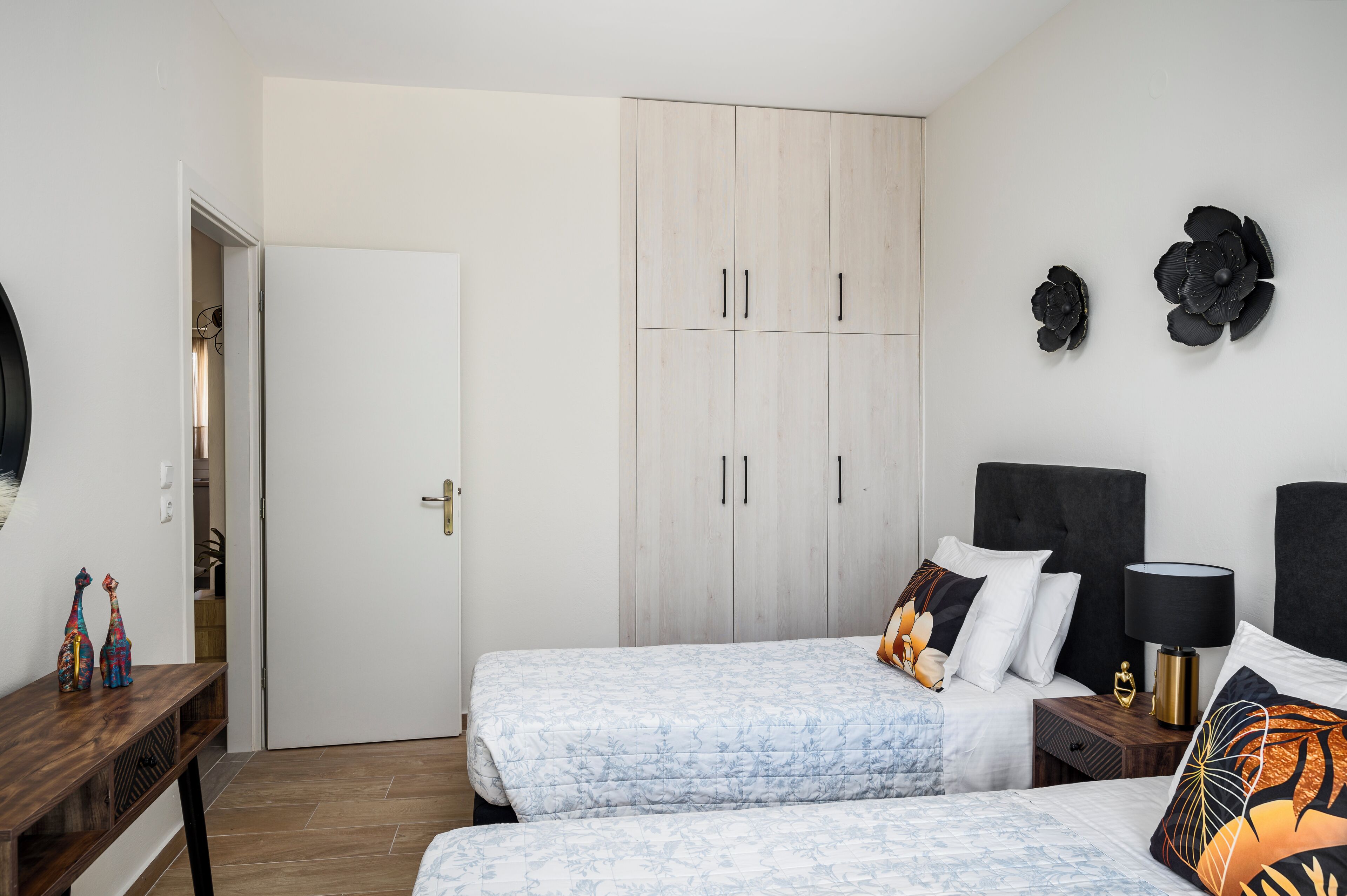 A bedroom with two beds, a wardrobe, a nightstand, and decorative wall art.