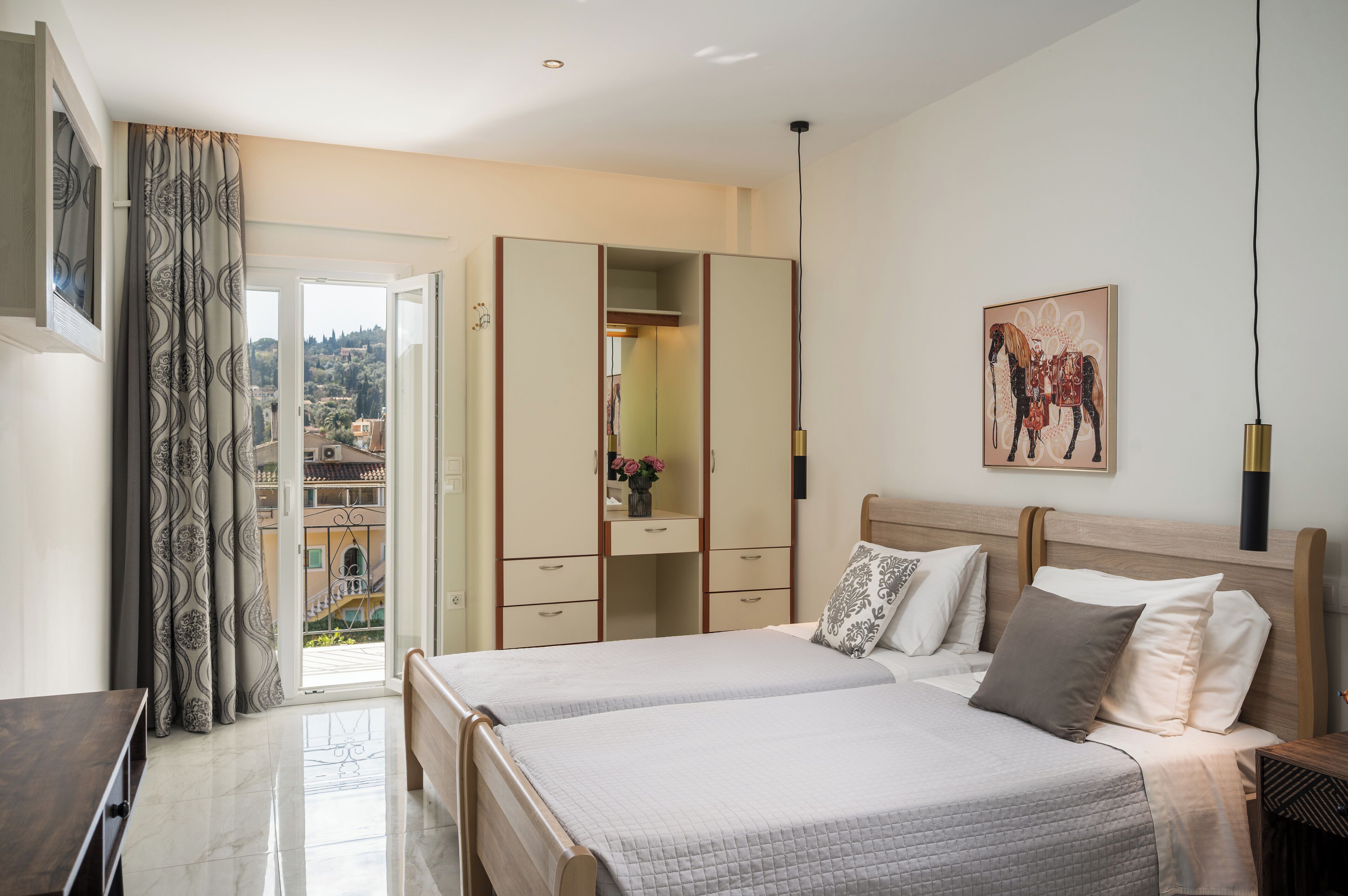 Quarto com duas camas, guarda-roupa, varanda e vista para a cidade.