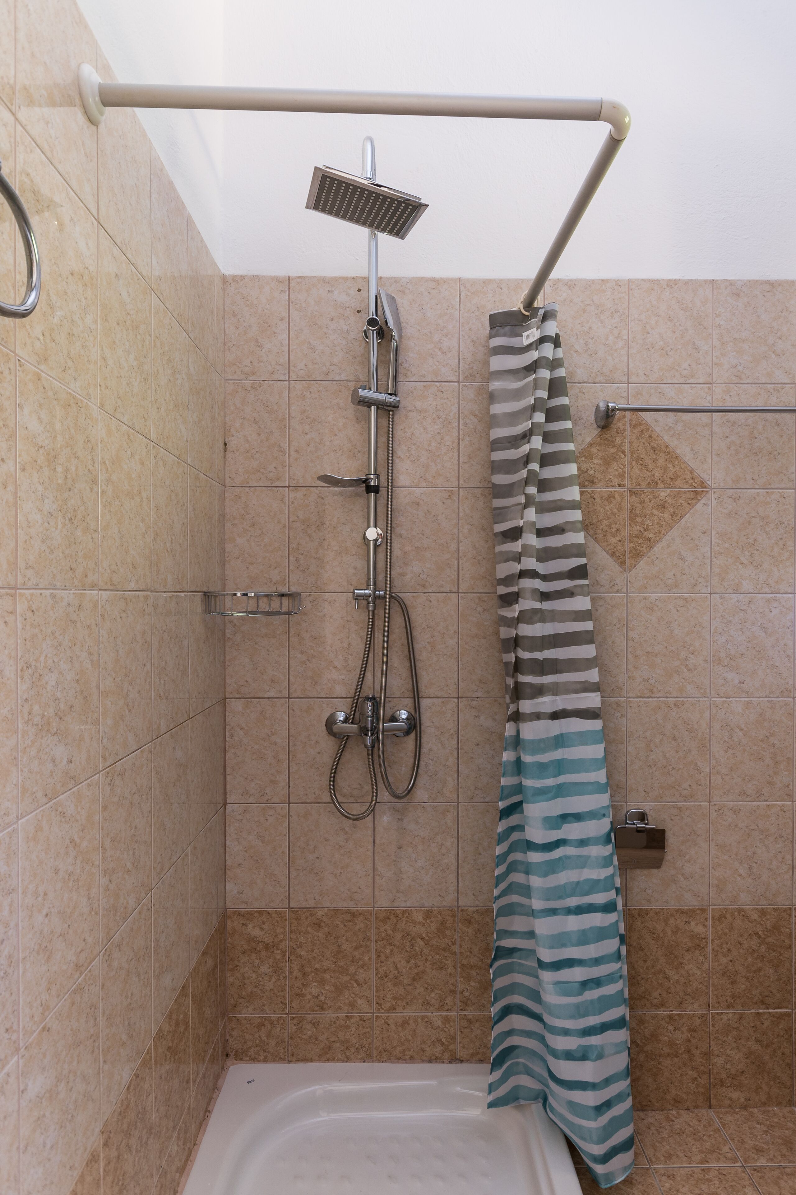 A shower area with a handheld showerhead, a towel rack, and a striped shower curtain.