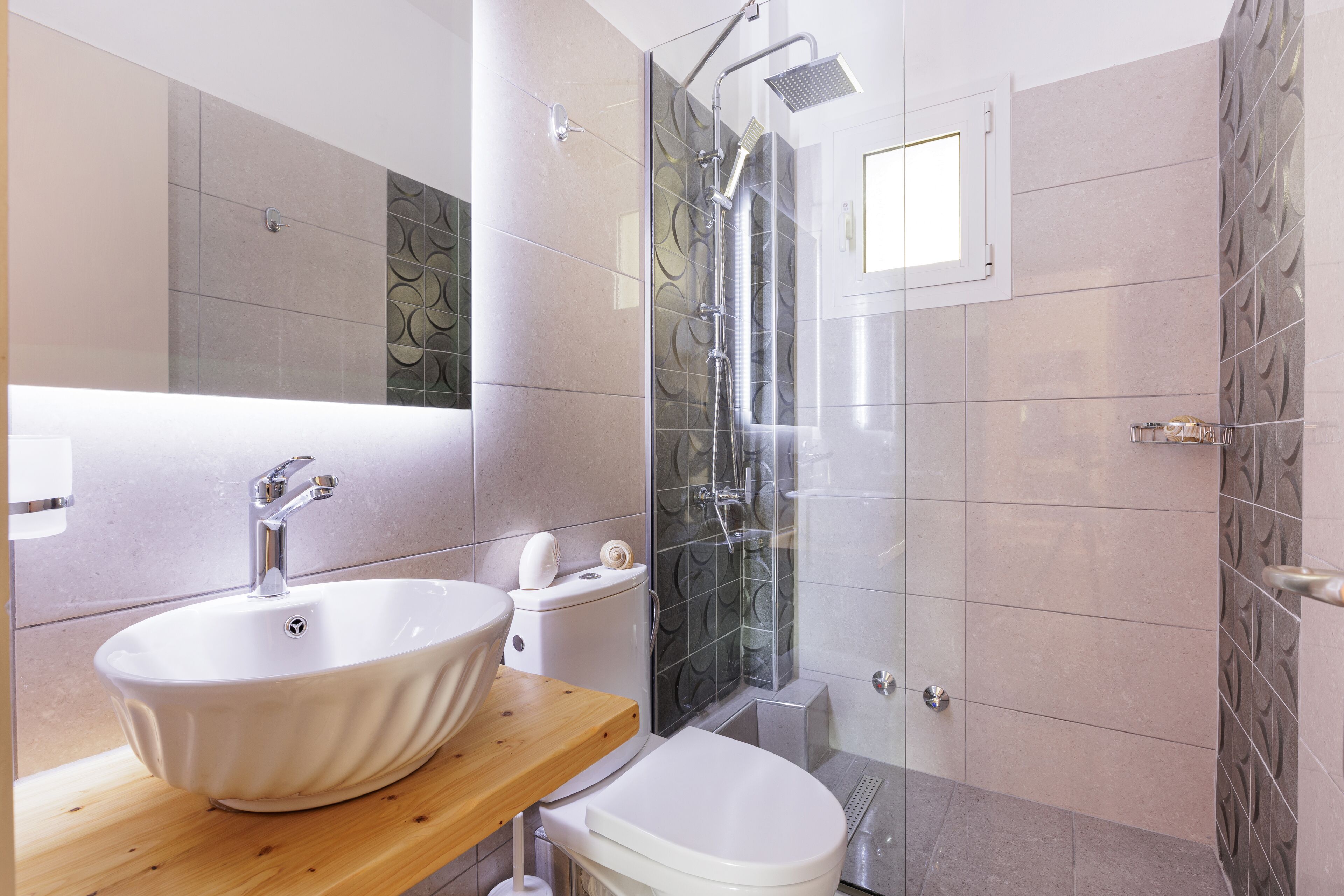 A modern bathroom with a freestanding sink, toilet, and glass-enclosed shower.