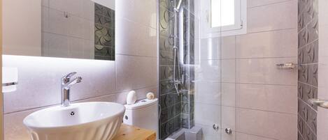 A modern bathroom with a freestanding sink, toilet, and glass-enclosed shower.