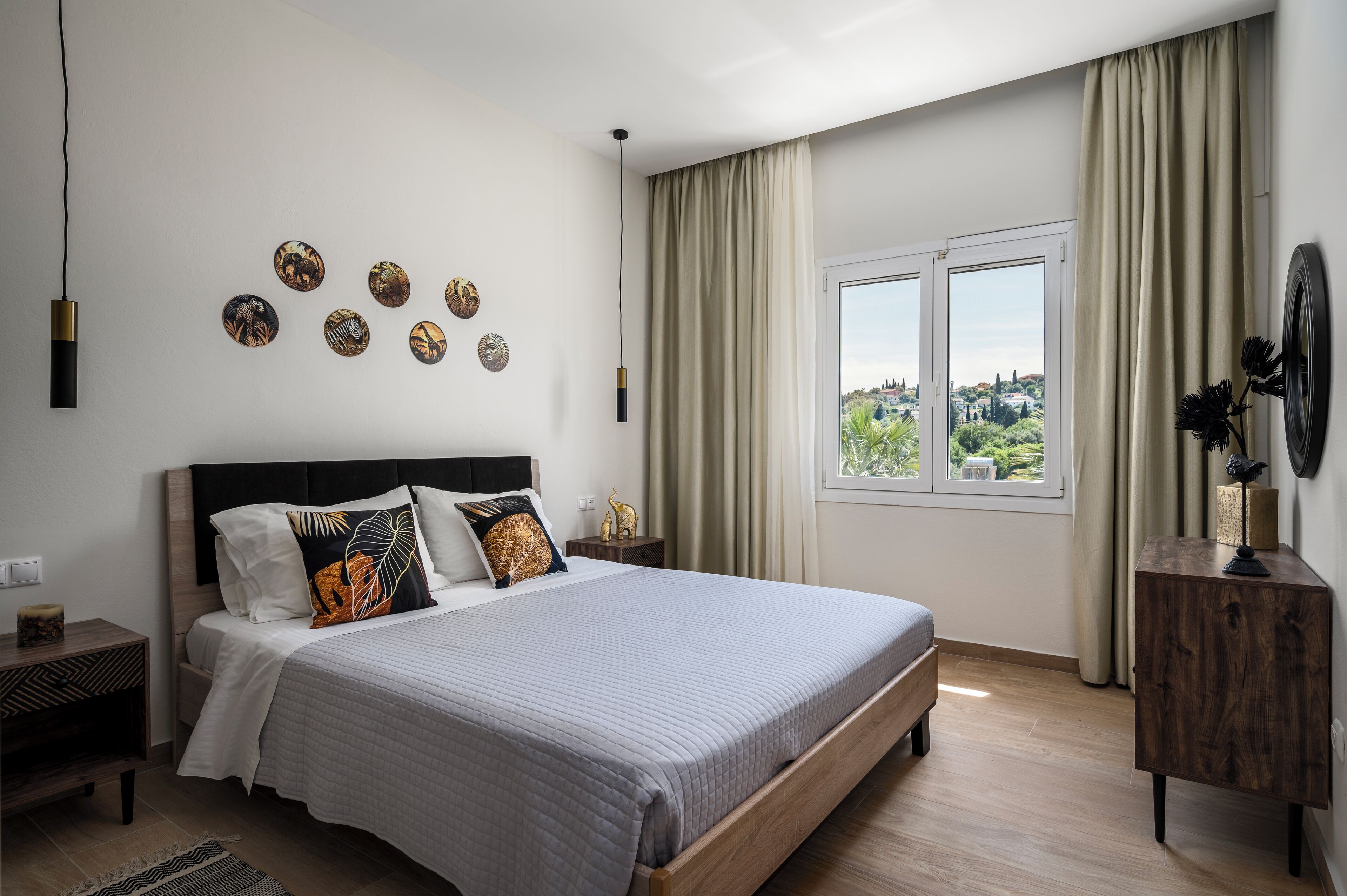 A bedroom with a bed, a nightstand, a dresser, a window with curtains, and wall art.