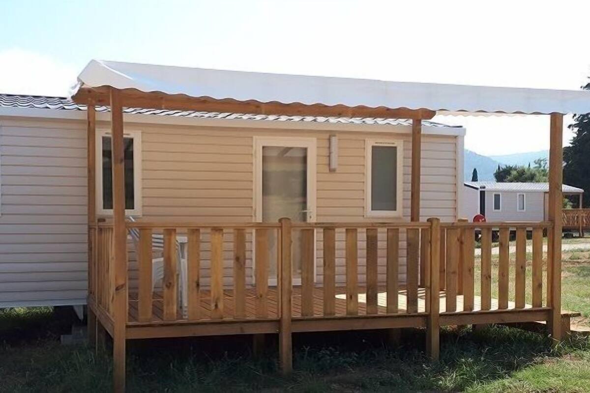 A mobile home with a wooden deck and a covered porch.