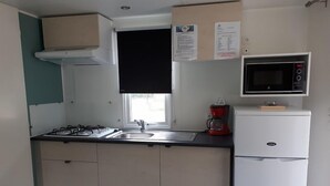 Une petite cuisine équipée d’une cuisinière à gaz, d’un évier, d’un four à micro-ondes et d’un petit réfrigérateur.