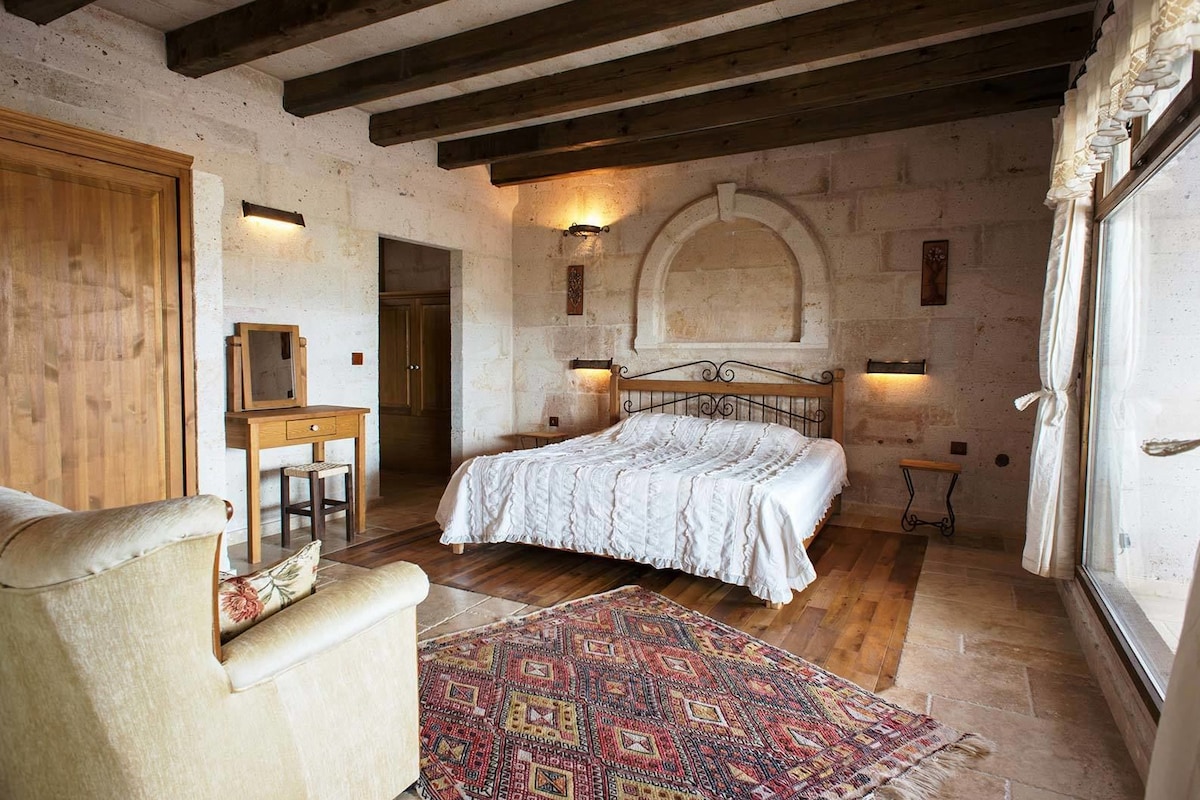 Un dormitorio con una cama de madera, un escritorio, una silla y una alfombra estampada.
