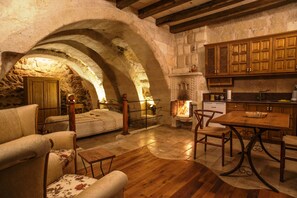 A rustic interior with a stone archway, wooden furniture, and a fireplace.