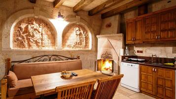 Eine rustikale Küche mit Kamin aus Stein, Holzmöbeln und einer Steinwand mit Schnitzereien.