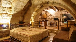 Um quarto rústico com cama, sofá, mesa e lareira de pedra.
