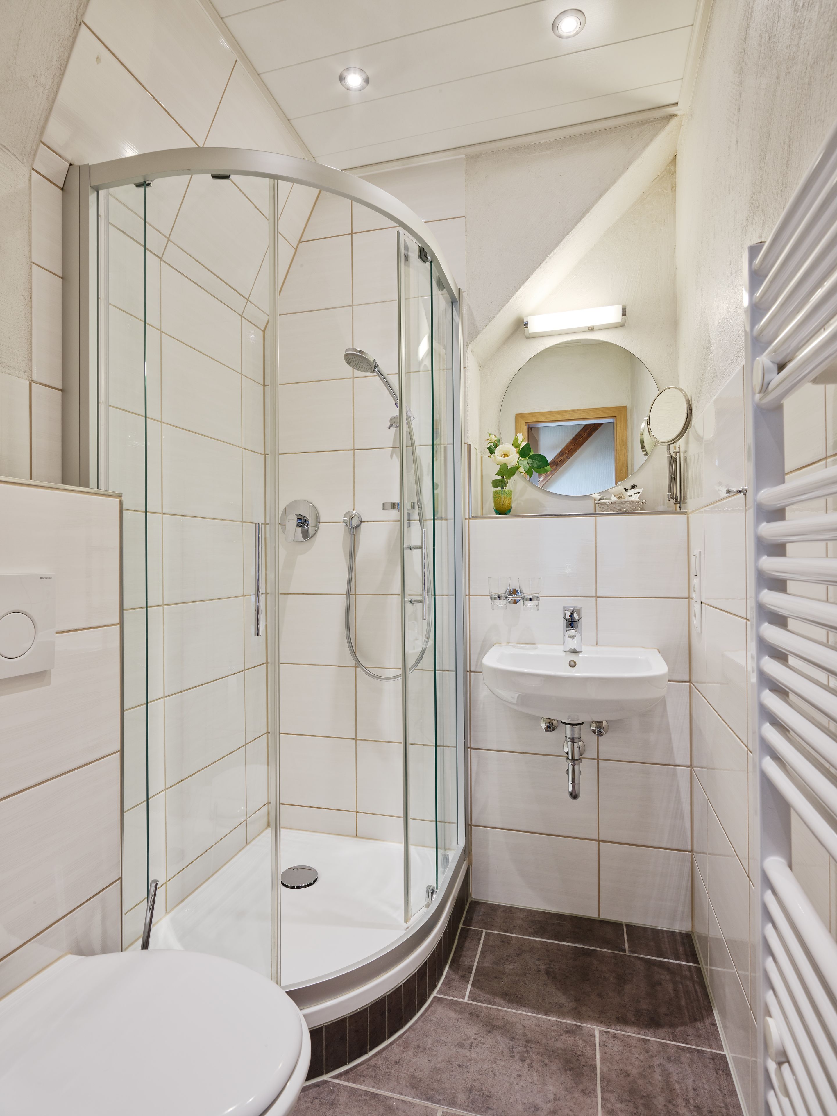 A modern bathroom with a glass-enclosed shower, a white sink, and a toilet.