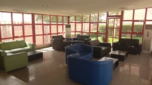 A spacious lobby with large windows, multiple seating areas, and a central air conditioning unit. - Nelseno Hotel (Abuja)