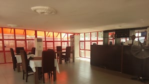 A restaurant with tables and chairs, a counter, and a fan. - Nelseno Hotel (Abuja)