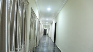 A long, narrow hallway with a shiny tiled floor and white walls. - Nelseno Hotel (Abuja)