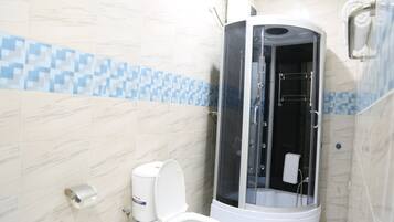A bathroom with a toilet, a shower enclosure, and a tiled wall.