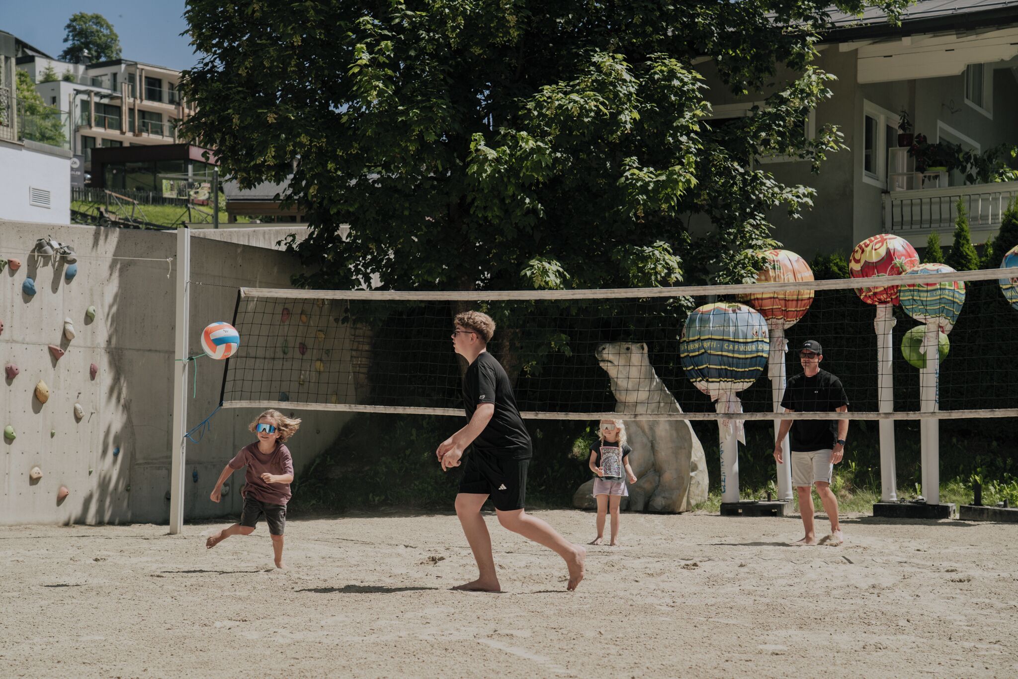 A sandy volleyball court with climbing walls in the background.
