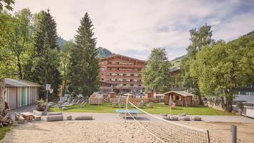Relax in a serene outdoor setting surrounded by lush greenery and mountain views, with a volleyball court and comfortable seating areas.