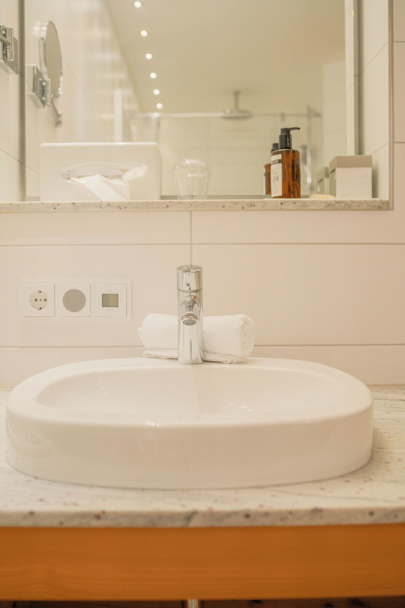 A bathroom with a round white sink, a mirror, and a towel on the counter.