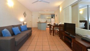 A living room with a sofa, TV, and a dining area with a table and chairs.