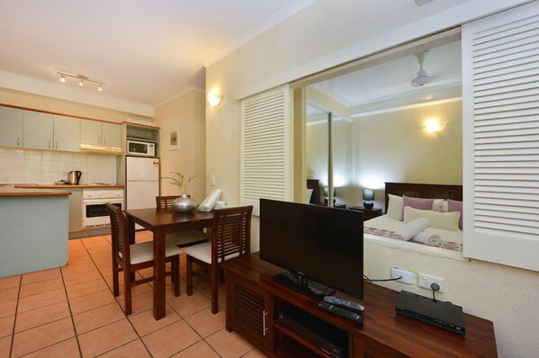 Una habitación de hotel compacta con kitchenette, zona de comedor, televisión y cama con vistas.