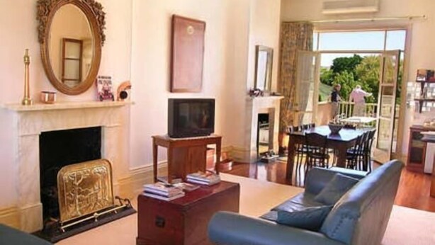 A living room with a fireplace, a television, and a sofa. - Fire Station Inn - 1 bedroom spa suite (Loggia) (Adelaide North)
