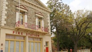 A fire station with a stone facade, large yellow garage doors, and a red sign above the entrance. - Fire Station Inn - 1 bedroom spa suite (Loggia) (Adelaide North)