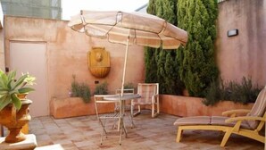 A patio with a table and chairs, an umbrella, and a wall-mounted decorative item. - Fire Station Inn - 1 bedroom spa suite (Loggia) (Adelaide North)