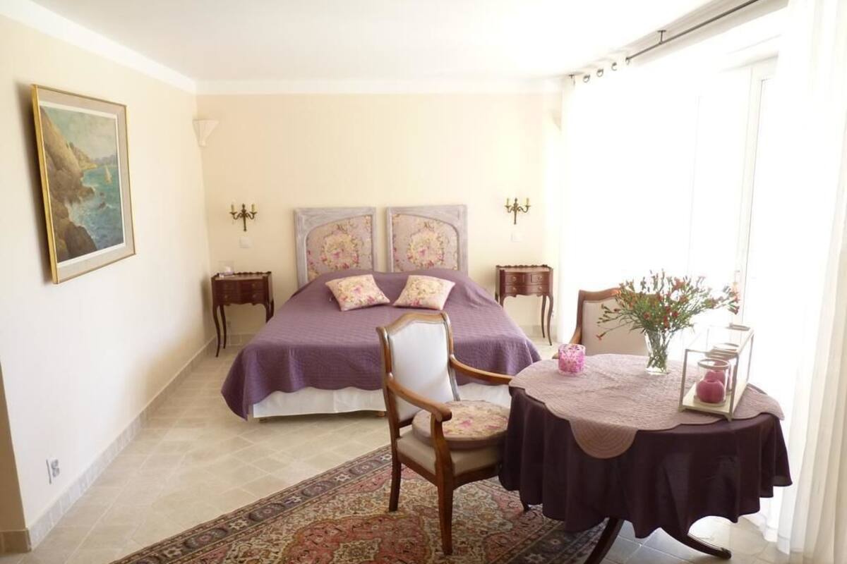 A bedroom with a bed, a chair, a table, and a rug.