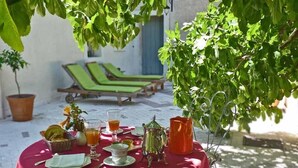 A table set outdoors with a red tablecloth, surrounded by greenery. - La Royante (Aubagne)