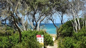 A pathway leading to a beach with a sign indicating a 145-meter distance to the sea.