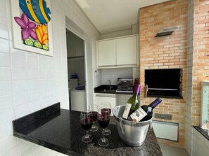 A kitchen with a black countertop, a wine bottle, and glasses of red wine.