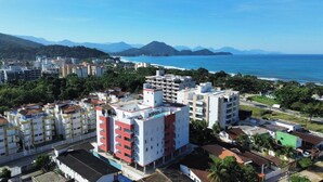 A coastal cityscape with modern buildings, a beach, and mountains in the background. - EXCELLENT APARTMENT 41 - SEA VIEW, TWO PARKING SPACES, ABSOLUTE HYGIENE, WE HAVE OTHER OPTIONS. (Ubatuba)