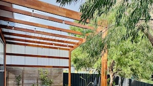 Une terrasse en bois avec une pergola, une table ronde et des chaises.