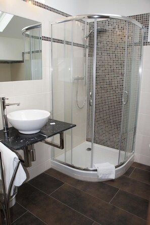 A modern bathroom with a glass-enclosed shower, a white sink, and a black countertop. - Hotel Muschinsky (Bad Lauterberg)