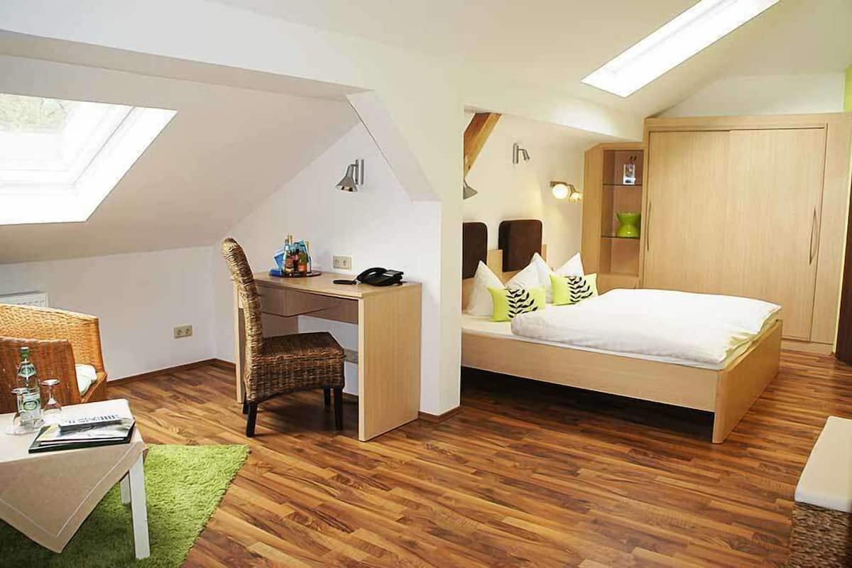 Ein Schlafzimmer mit Oberlicht, einem Bett, einem Schreibtisch und einem Sessel.