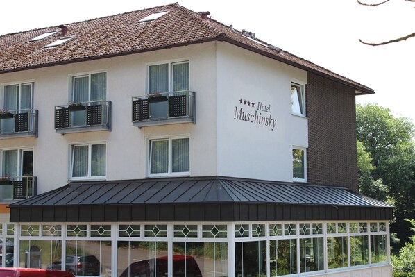 A hotel building with a white facade, multiple windows, and a sign indicating it is a 4-star hotel. - Hotel Muschinsky (Bad Lauterberg)